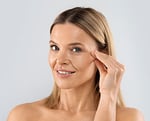 blonde middle aged woman playing with face skin